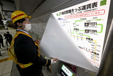 値上げされた運賃表に変更する職員＝18日未明、JR品川駅