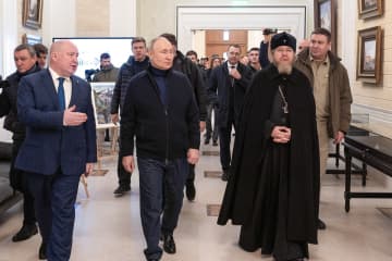 18日、クリミア半島セバストポリ市で、ラズボジャエフ市長（前列左）らと子どもの教育施設を視察するロシアのプーチン大統領（中央）（タス＝共同）