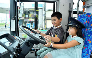 バスの運転席に試乗し、笑みを浮かべる子ども＝鶴岡市・エスモール