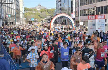 熊本城をバックにスタートするフルマラソンのランナーたち＝18日午前、熊本市中央区の通町筋電停前（上杉勇太）