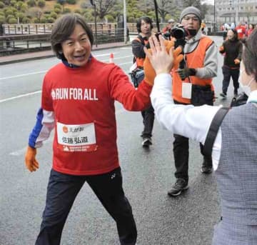 沿道の応援にハイタッチで応える佐藤弘道さん＝16日、熊本市中央区