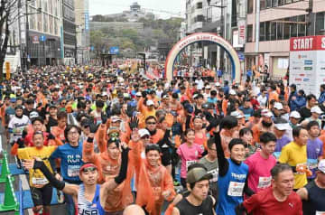 熊本城をバックに、フルマラソンの部でスタートする市民ランナーたち＝16日午前9時過ぎ、熊本市中央区（上杉勇太）