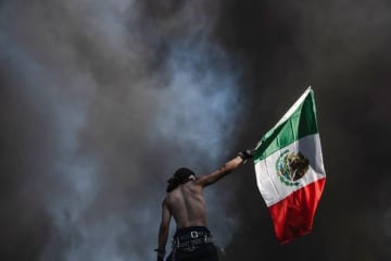 ロス抗議デモを象徴するメキシコ国旗　掲げているのはだれか