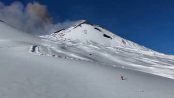 噴火を背にスキーヤーが滑降　イタリア