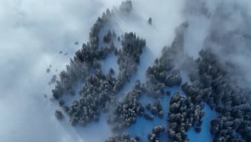 雪原を流れる雲、白い冬景色に　中国新疆ウイグル自治区