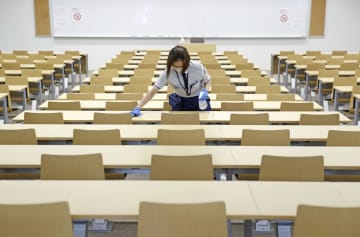 大学入学共通テストを前に、会場となる上智大の教室で机を消毒するスタッフ＝14日午後、東京都千代田区