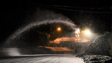 沿道によけた雪をかき出すロータリー除雪車。吐き出す雪が、路上に白いアーチを描く＝飛騨市古川町数河、国道41号