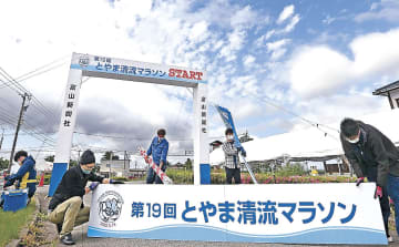 とやま清流マラソンの設営を進めるスタッフ＝富山市の神通川水辺プラザ自然ふれあい学習館前