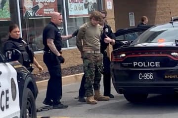 14日、銃撃事件があった米ニューヨーク州北部バファローのスーパーで警察官に拘束された男性（BigDawg提供・ロイター＝共同）