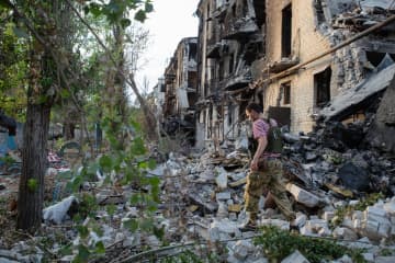 23日、ウクライナ東部ルガンスク州セベロドネツクで、破壊された建物脇を歩く地元の男性（タス＝共同）