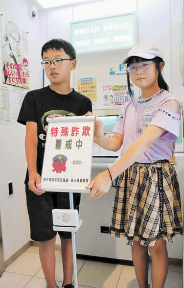 ATM前に新装置を置く武田君（左）と後藤さん＝南三陸町のJA新みやぎ志津川支店