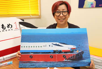 西九州新幹線かもめの海上輸送の写真を見せる久米さん。好きが高じて髪も赤く染めた＝大村市内