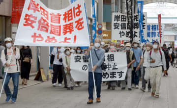 国葬の中止を求める横断幕などを掲げて繁華街を歩く参加者