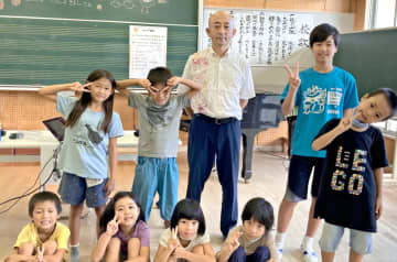 講話をした竹島喜芳さん（後列中央）と児童たち＝15日、東村・高江小学校