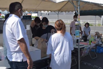 フードパントリーで食料品や日用品を受け取る女性(手前)=土浦市内