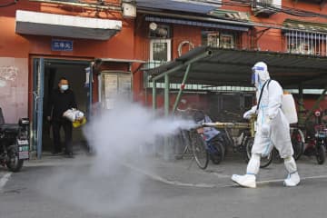 新型コロナ対策で住宅街を消毒する作業員＝25日、北京（共同）