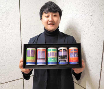 小田急グループの電車がデザインされた日本酒缶を手にするアグナビの玄成秀代表取締役CEO