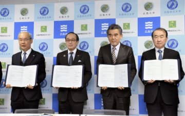 平和研究機構の設立に向けた連携協定書を手にする広島市の松井一実市長（左から2人目）ら＝25日午後、広島市
