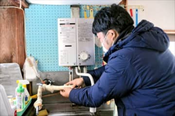 凍結した水道管を修理する業者＝25日午前、川俣町