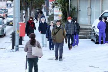 路面凍結した坂道を慎重に歩く人たち＝25日午前8時17分、長崎市赤迫2丁目