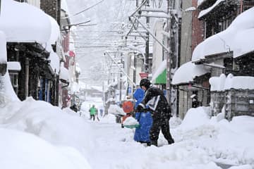 雪が降りしきる中、民家の前の除雪作業に追われる町民ら＝25日午前9時37分、智頭町智頭