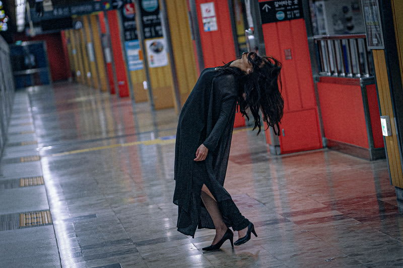 A frazzled woman with long black hair suddenly hits her own head in the "Ochs Station Ghost" special video