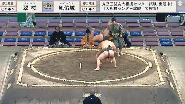 A tall sumo wrestler shows off his amazing physical abilities!Gyoji is surprised by the unexpected cartwheel and says, ``Wow!'' The hall erupts in excitement.