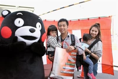 くまモンラッピング電車を利用した外国人観光客として１０万人目となった梁思偉さん（中央）と家族