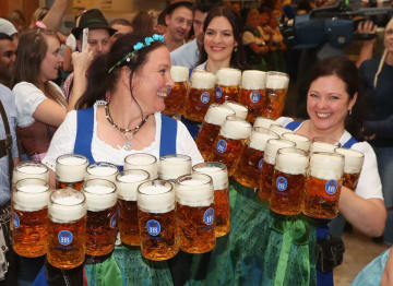 ドイツ・ミュンヘンで始まった伝統のビール祭り「オクトーバーフェスト」で、ジョッキを運ぶウェイトレス=22日(ゲッティ=共同)